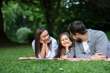 Happy family spending time together on checkered picnic blanket outdoors