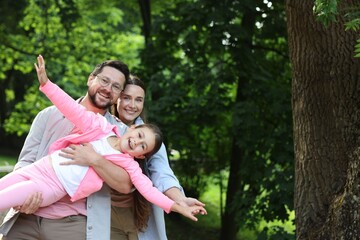Family portrait of smiling parents and daughter outdoors