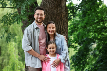 Fototapeta premium Family portrait of smiling parents and daughter outdoors
