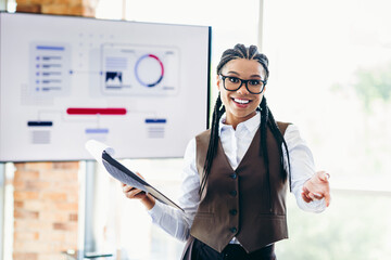 Young businesswoman presenting analytics in modern office setting with charts and reports for a...