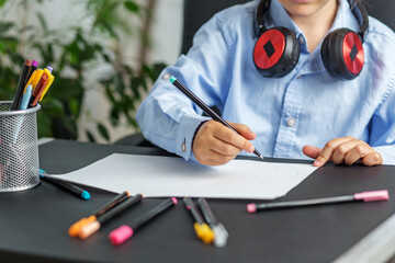 Close-up of child drawing with pencil at desk. Back to school