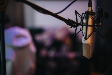 Close-up of a professional microphone in a recording studio setting, capturing the atmosphere of...