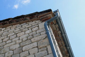 Gouttière en zinc gris sur le mur en pierre