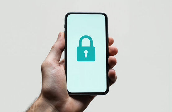 Man holds smartphone displaying locked padlock icon. Represents phone security, privacy, restricted access. Digital safety, protection against unauthorized entry, data encryption for user information.