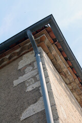 Gouttière en zinc gris sur le mur en pierre