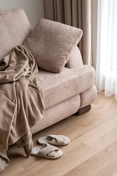 Cozy living room design interior, soft velure sofa, pillow, crumpled fleece blanket and sleepers, comfortable place for rest or daytime sleep