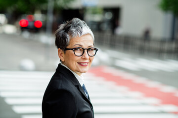 Professional mature businesswoman in urban environment, exuding confidence and elegance while...