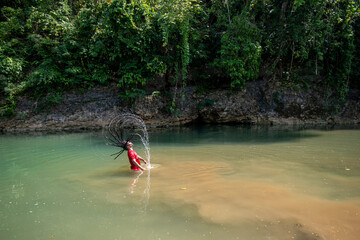 A man shaking his hair in the water, Playing splashing with his hair in the river, Photo from the side