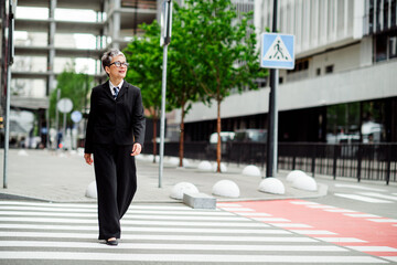 Successful businesswoman crossing an urban street in formalwear, showcasing confidence and elegance...