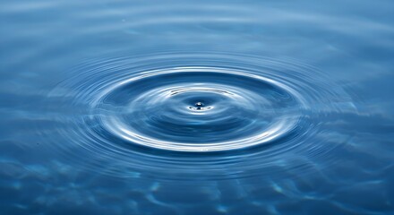 Close up of a single water drop creating concentric ripples on a calm blue liquid surface