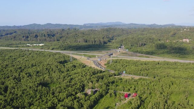 View of highway intersection surrounded by lush greenery in rural landscape. Aerial view highway intersection in Georgia. Drone fly over ring roads, highway between forest in Georgia,  Eastern Europe.