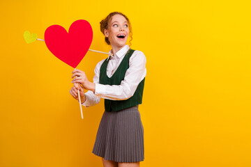 Cheerful Student Holding Heart Prop on Yellow Background Promoting Love and Happiness in Stylish...