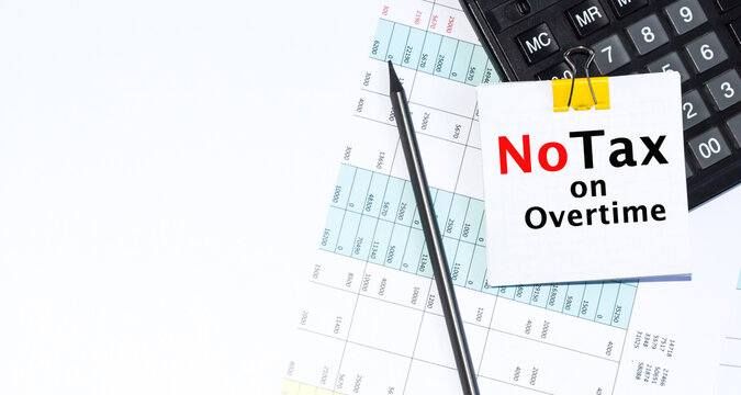 No Tax ON Overtime TEXT is written on Desktop with calculator, pencil on blue background. Conceptual overtime pay symbol. Copy space.