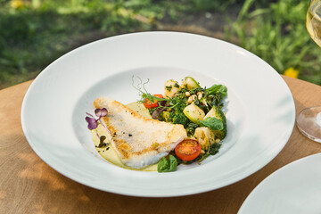 Pike perch fillet with vegetable garnish and beurre blanc, bright natural lighting, overhead restaurant plating
