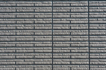 A close-up of a gray brick wall with a horizontal pattern and vertical seams.