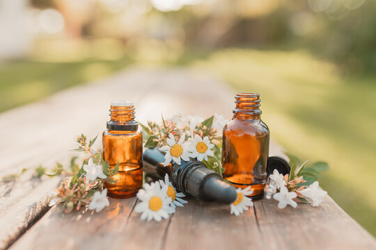Collection of various amber essential oil bottles with fresh flowers