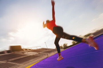 Silhouette of  young woman running sprinting at the racetrack with speed zoom blur effect. Fit runner fitness runner during outdoor workout at racetrack.