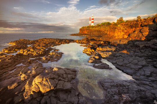 View of Albion Lighthouse standing proud against the sky, rocky shores meet the sea, and tidepools reflect the sky's palette, creating a coastal symphony, Mauritius.