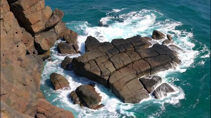 Jagged coastal rocks meet crashing waves under a bright sky - Powered by Adobe