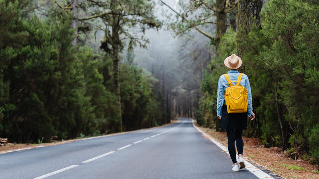 Woman on road through green forest on Tenerife, El Teide National Park, Canary Islands, Spain - Powered by Adobe