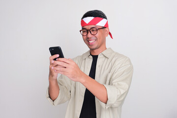 Indonesian man smiling happy when looking at his phone during independence day celebration