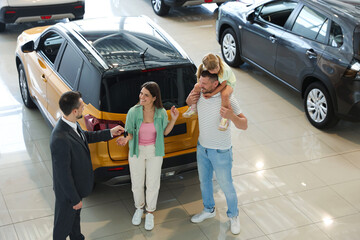 Salesman giving car key to happy family in salon