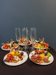 Creative assortment of charcuterie canapes and cheese bites garnished with olives and herbs served on elegant white tablecloth setting