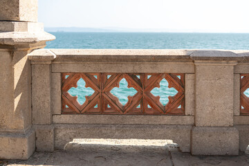Close-up of an ornate historic stone balustrade with terracotta inlays, overlooking the blue...