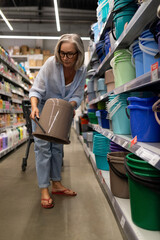 Fototapeta premium Middle-aged woman shopping in a home improvement store exploring various household and garden items