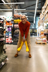 Middle-aged woman enjoys shopping experience in a retail home goods store exploring various product...