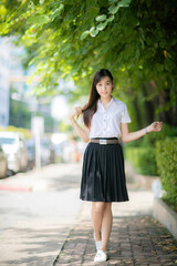 A cute college student with an Asian look stood proudly in front of the university emblem, posing...