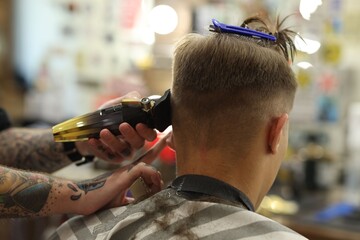 Professional barber making stylish haircut in barbershop, closeup