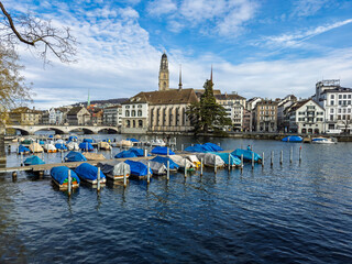Panoramic view of historic Zurich cityscape with covered boats docked along Lake Zurich waterfront...