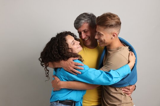 Happy friends hugging each other on grey background - Powered by Adobe