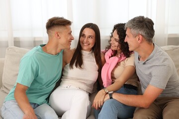 Happy friends hugging and having fun on sofa at home