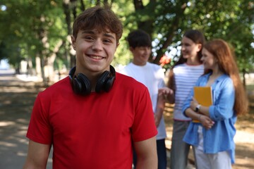 Portrait of teenage boy with headphones in park, selective focus