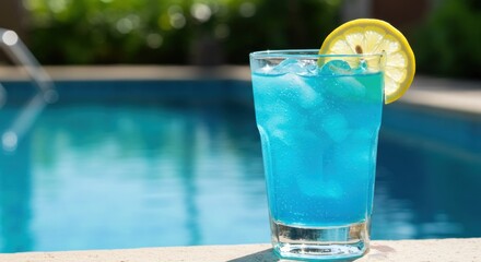 A vibrant blue cocktail with ice and a lemon garnish sits poolside, the refreshing drink a contrast to the clear water