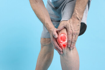 Arthritis. Senior man suffering from knee pain on light blue background, closeup. Illustration of...