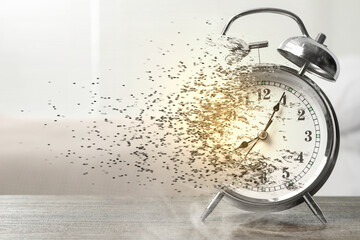 Time running out. Silver alarm clock dissolving on table