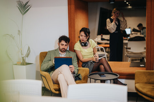 A vibrant office environment featuring colleagues engaged in a discussion, utilizing digital devices for productivity, set within a modern workplace designed for collaboration and open communication.