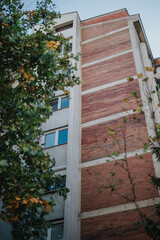 An urban apartment building with a brick facade and concrete frame viewed from below, framed...