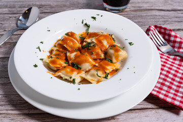 Ravioli with tomato sauce and parsley garnished on white plate