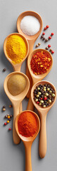 Vertical arrangement of five rustic wooden spoons filled with colorful culinary spices, golden turmeric powder, fine white powder, coarse red chili flakes, rich orange ground spice,peppercorns.