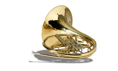 French horn on a white table. Beautiful polished musical instrument. Light background.