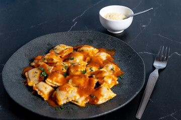 Ravioli pasta with tomato sauce and parsley on dark plate