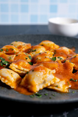 Ravioli pasta with tomato sauce and parsley on dark plate. Vertical Orientation