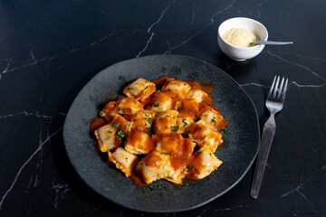 Ravioli pasta with tomato sauce and parsley on dark plate