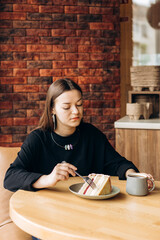 Young woman drinking black filter coffee with cake in morning cafe scene.