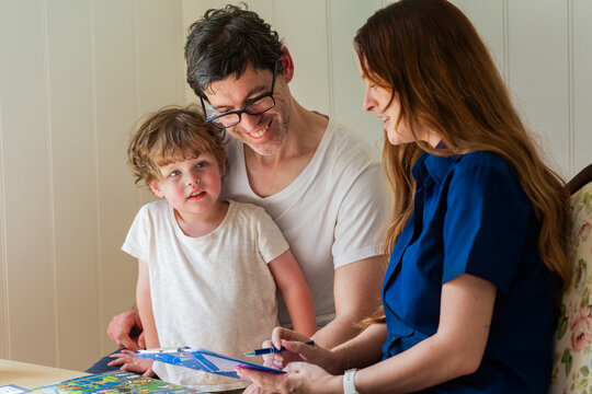 Parent with child talking with speech pathologist clinician holding paperwork during assessment
