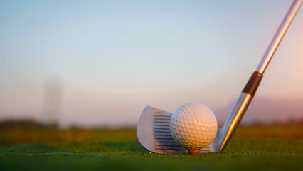 Golf clubs and balls on a green lawn in a beautiful golf course with morning sunshine.